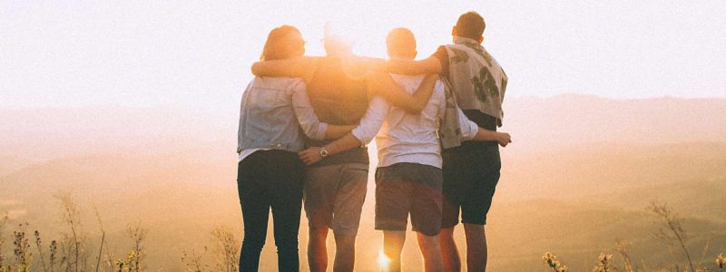 Group of friends enjoying a sunset on a hillside